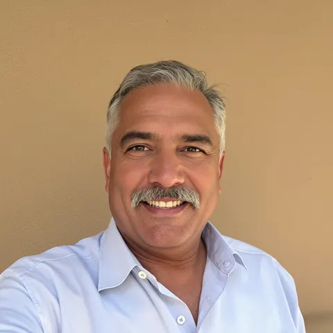 A selfie of a smiling man with a grey mustache, before restyling